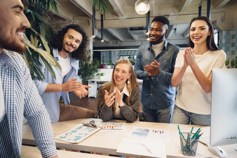 Team of diverse coworkers in modern office discuss their project together Free Photo