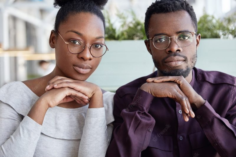 Teamwork and cooperation concept. successful african american female and male colleagues sit close to each other, wears spectacles Free Photo