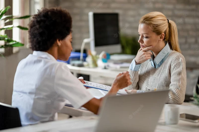 Thoughtful woman going through medical test results with her doctor at clinic Free Photo