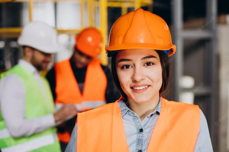 Three people discussing a plan at a factory Free Photo