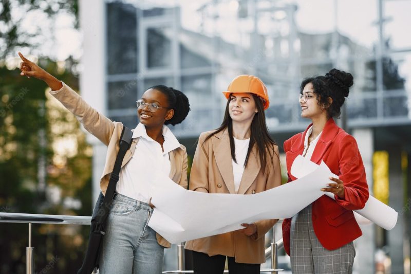 Three women working as architectors on a constraction and making a decision about plan of a building Free Photo