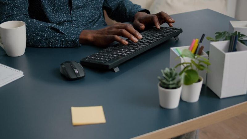 Top view of black man african american hands typing on computer keybord on a blue desk. remote worker using pc, working from home, browsing searching online web internet communication Free Photo