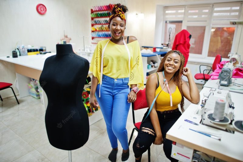 Two african dressmaker woman sews clothes on sewing machine at tailor office black seamstress girls Free Photo