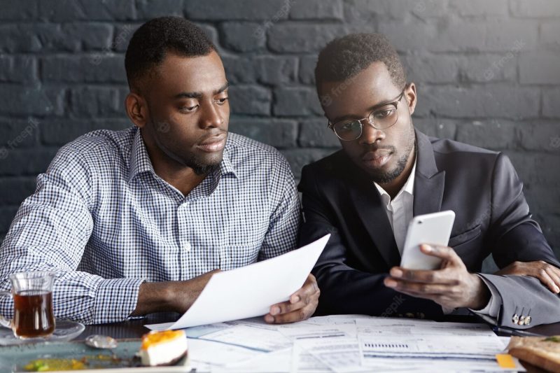 Two confident and serious African-American businessmen focused on paperwork Free Photo