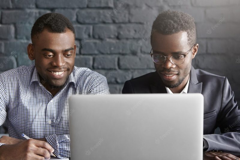 Two happy African colleagues using laptop Free Photo