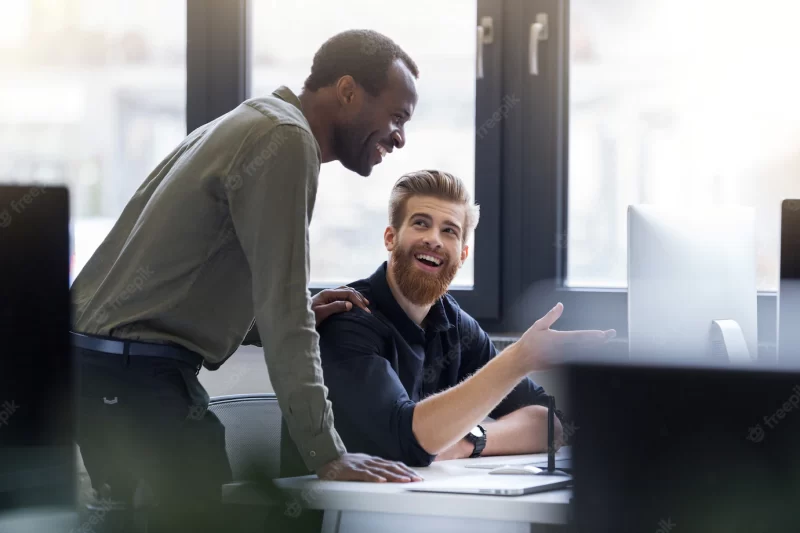 Two happy men working together on a new business project Free Photo