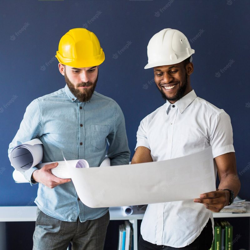 Two male engineers looking at blueprint Free Photo