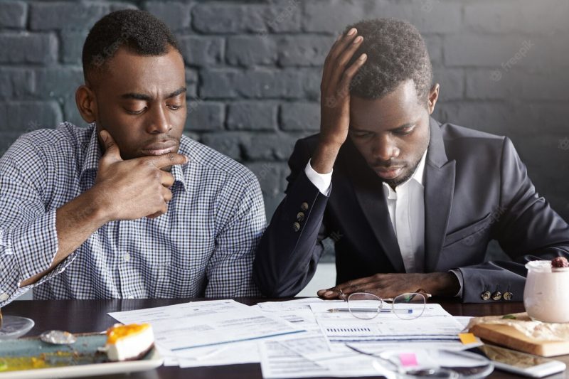 Two tired and depressed African-American businessmen doing paperwork Free Photo