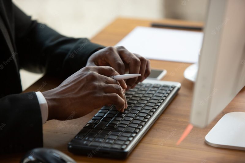 Typing text, close up. african-american entrepreneur, businessman working concentrated in office. looks serious and busy, wearing classic suit. Free Photo