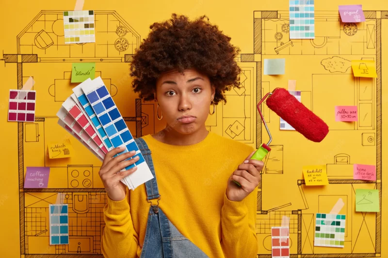 Unhappy tired young woman holds tools for repair, color samples, fatigue after wall painting or refurbishment, poses over creative design project. home repair or reconstruction work concept. Free Photo