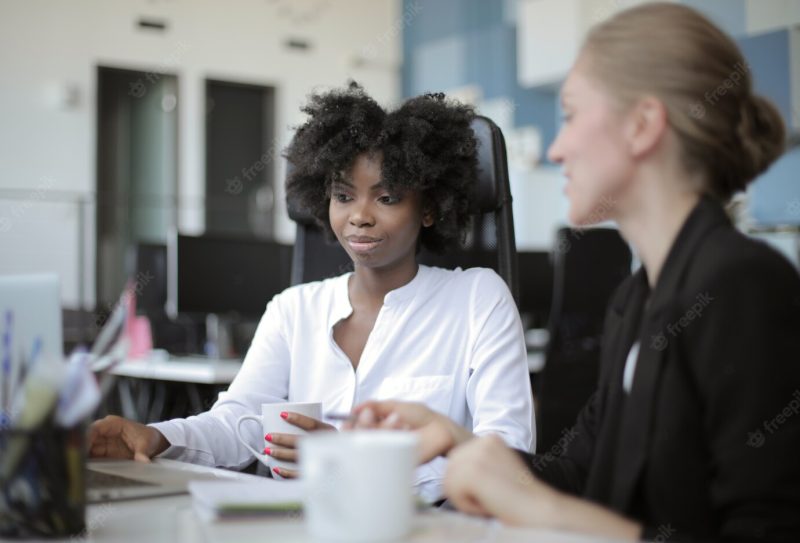 View of two female coworkers sitting side by side in an office-concept: rivalry, coworker Free Photo