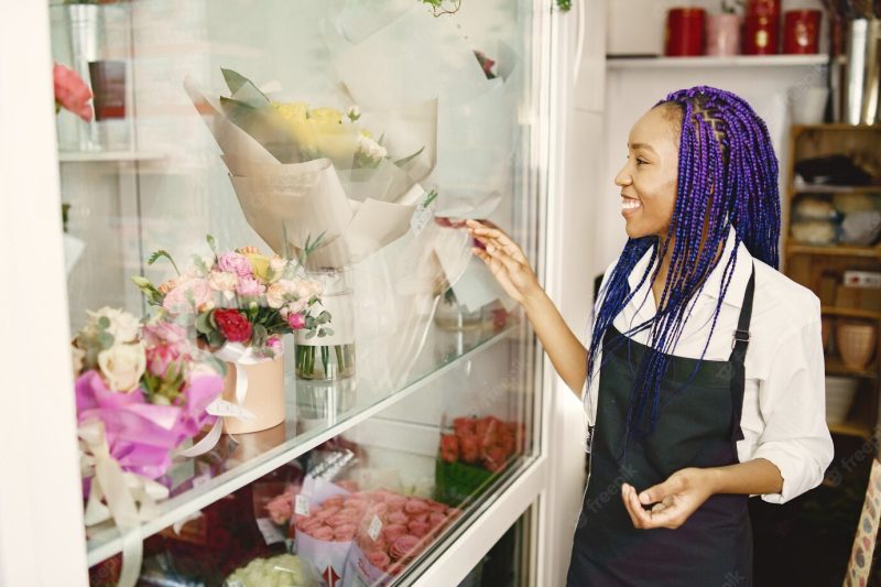 Woman manager standing at workplace. lady with plant in hands. happy female florist in floral center florist concept. Free Photo