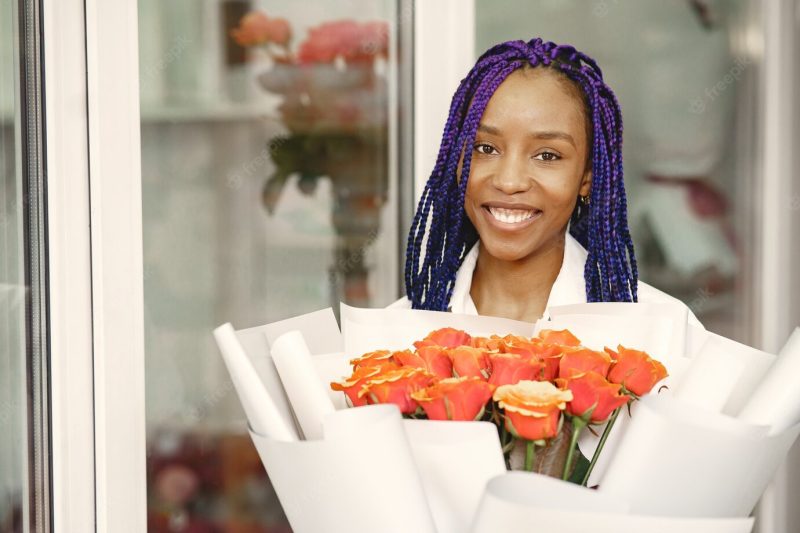 Woman manager standing at workplace. lady with plant in hands. happy female florist in floral center florist concept. Free Photo