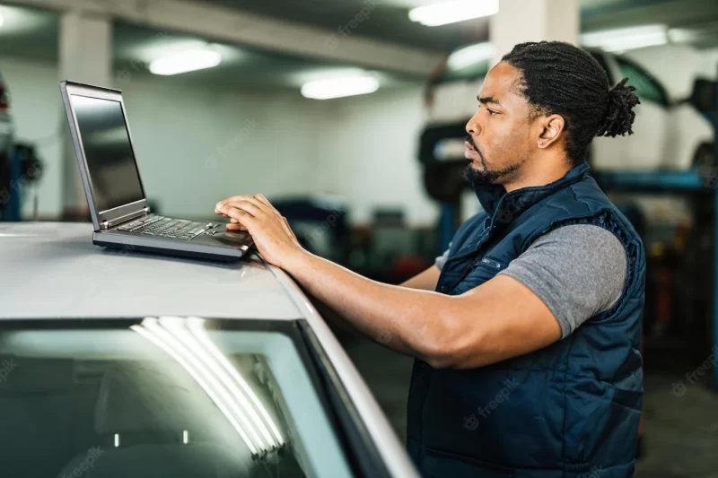 Young african american car mechanic using laptop in repair workshop Free Photo