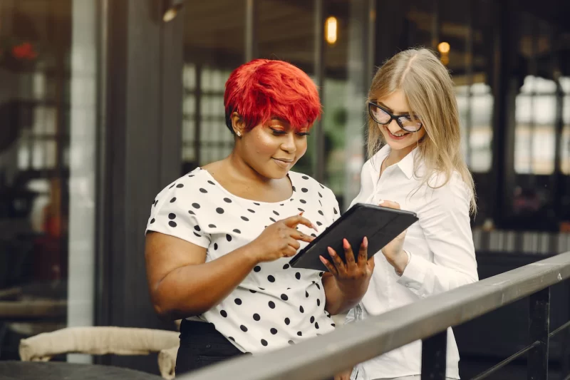 Young African American female working in an office. lady in a white blouse. Caucasian woman with her African colleague. Free Photo