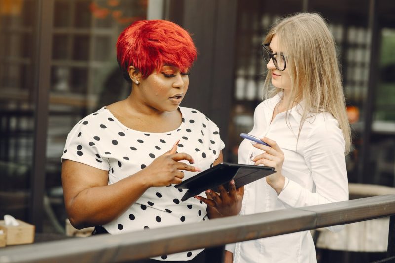 Young African American female working in an office. lady in a white blouse. Caucasian woman with her African colleague. Free Photo