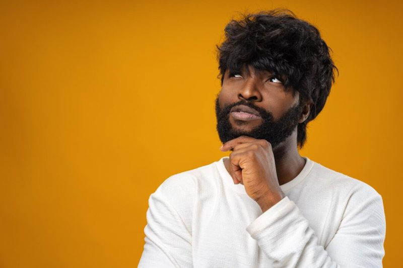 Young african american man thinking and touching his chin Free Photo