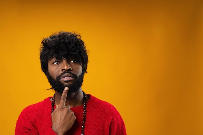 Young african american man thinking and touching his chin Free Photo