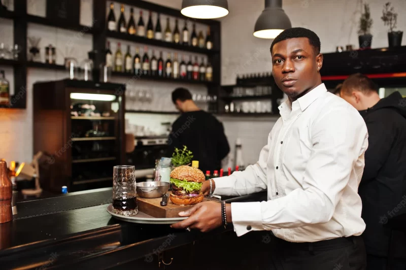 Young african american waiter man hold tray with burger at bar of restaurant Free Photo Young african american waiter man hold tray with burger at bar of restaurant Free Photo