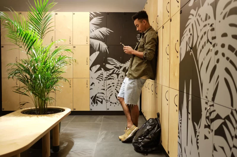 Young attractive serious casual African American man thoughtfully using cellphone in locker room alone Free Photo