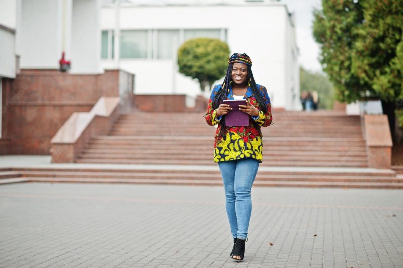 Young black female posed in the city african women single portrait she hold tablet on hand Free Photo