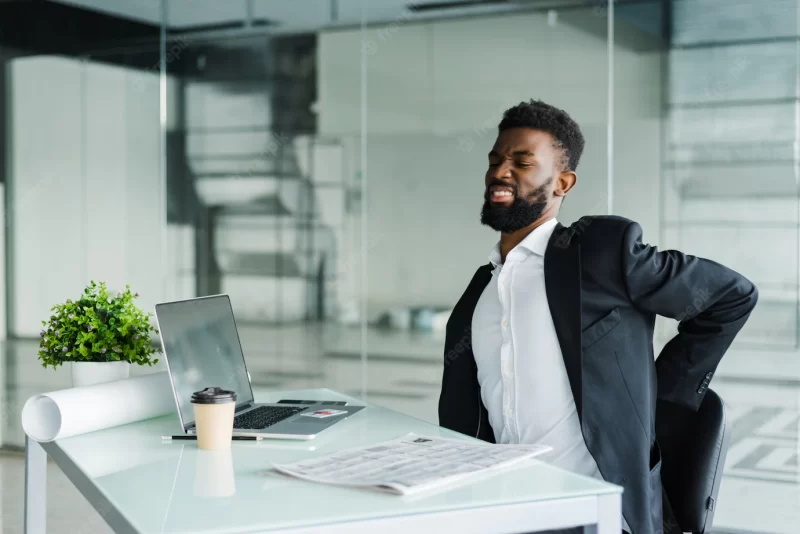 Young businessman in office at desk suffering from back pain in office Free Photo