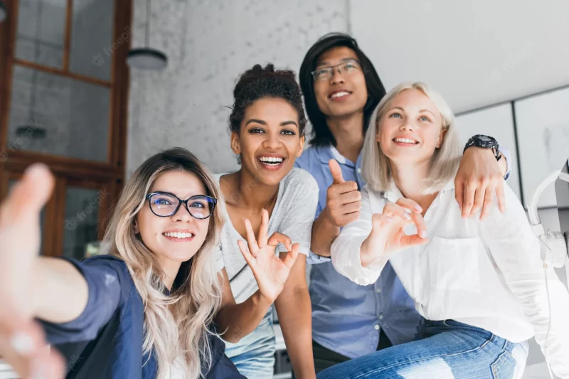 Young international office workers posing together and laughing during break Free Photo