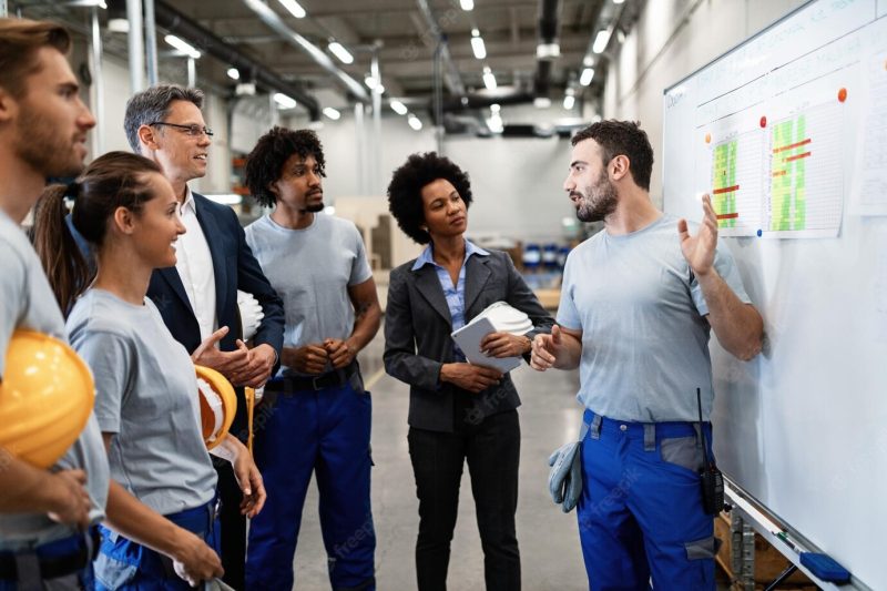 Young manual worker presenting new business strategy to company managers and his colleagues in a factory Free Photo