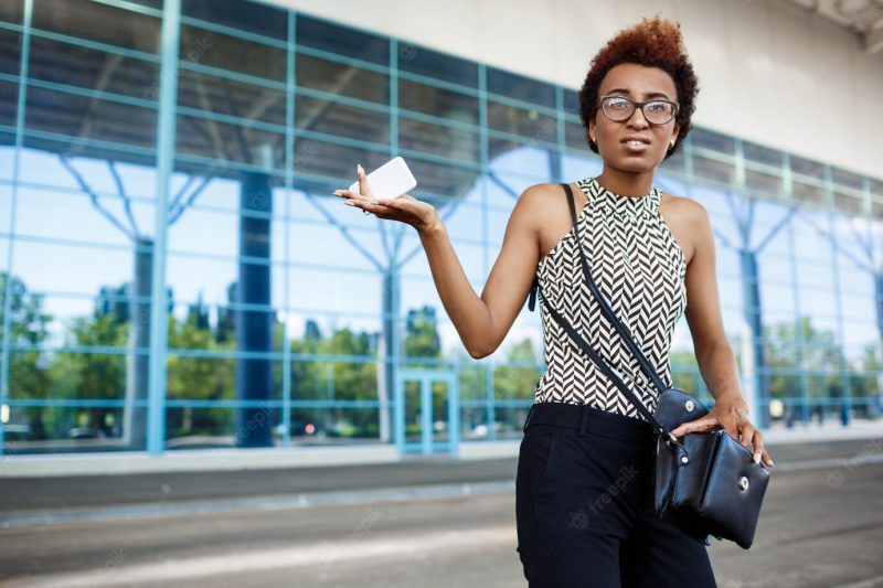 Young successful African businesswoman in glasses standing over business centre. Free Photo