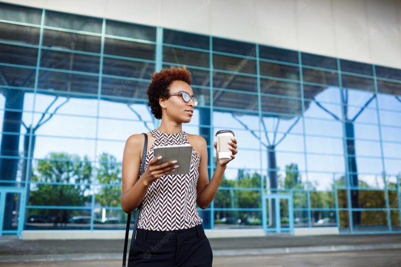 Young successful African businesswoman in glasses standing near business centre. Free Photo