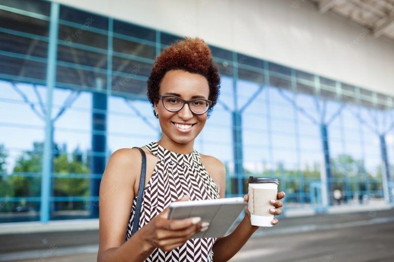 Young successful African businesswoman in glasses standing near business centre. Free Photo