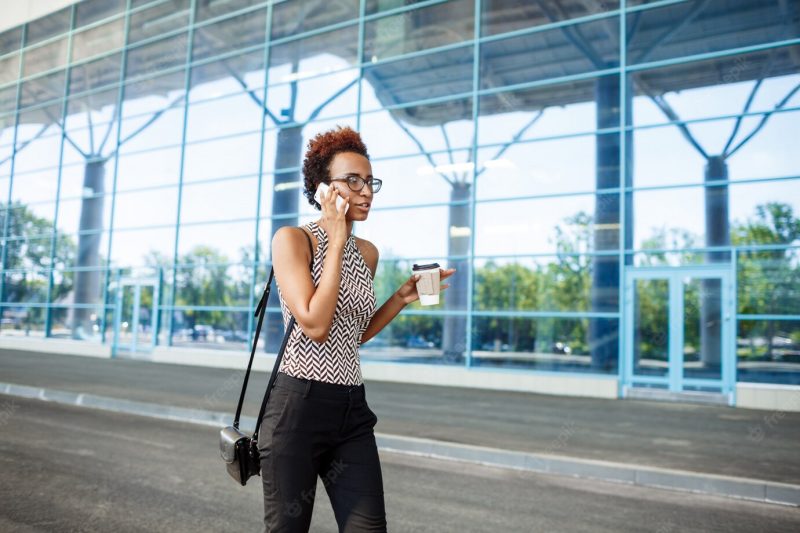 Young successful African businesswoman speaking on phone over business centre. Free Photo