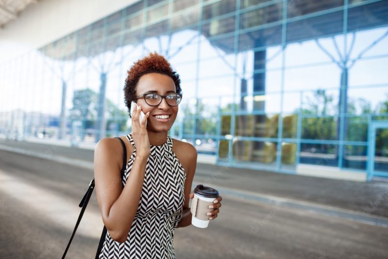 Young successful African businesswoman speaking on phone over business centre. Free Photo