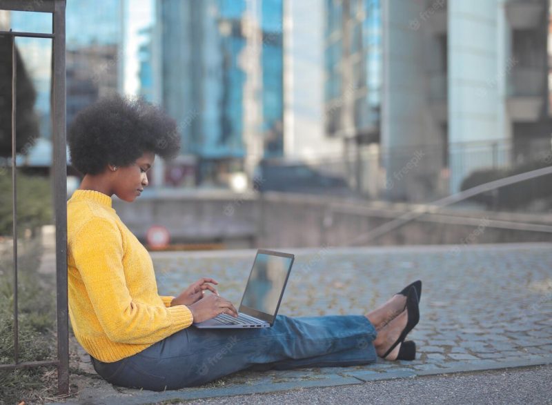 Young woman works with a computer in the city Free Photo