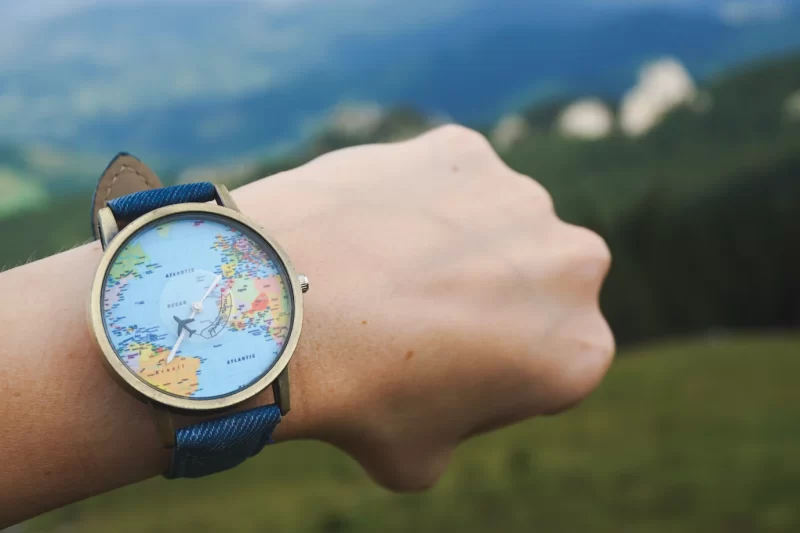 Closeup shot of a watch tied to a hand with world map on it Free Photo