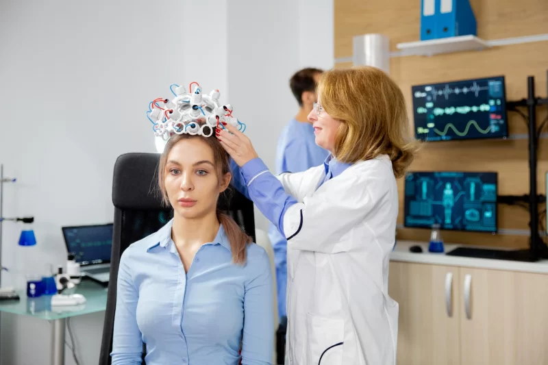Female scientist who puts brain waves scanning device on a female patient. clinical study of brain activity Free Photo
