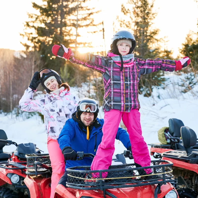 Happy family driving quad bike in winter mountains Free Photo