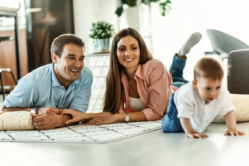 Happy parents enjoying while watching their baby boy crawling on the floor in the living room Free Photo