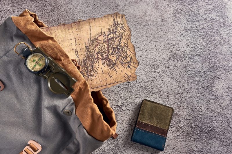 Top view closeup of a compass placed on a colorful fabric next to an ancient map and a wallet Free Photo